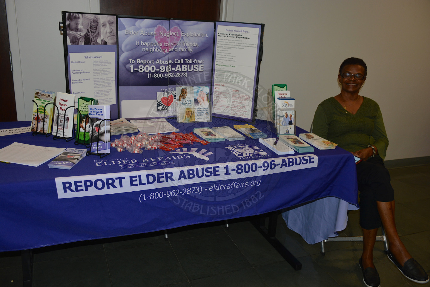 woman sitting at display table for Report Elder Abuse