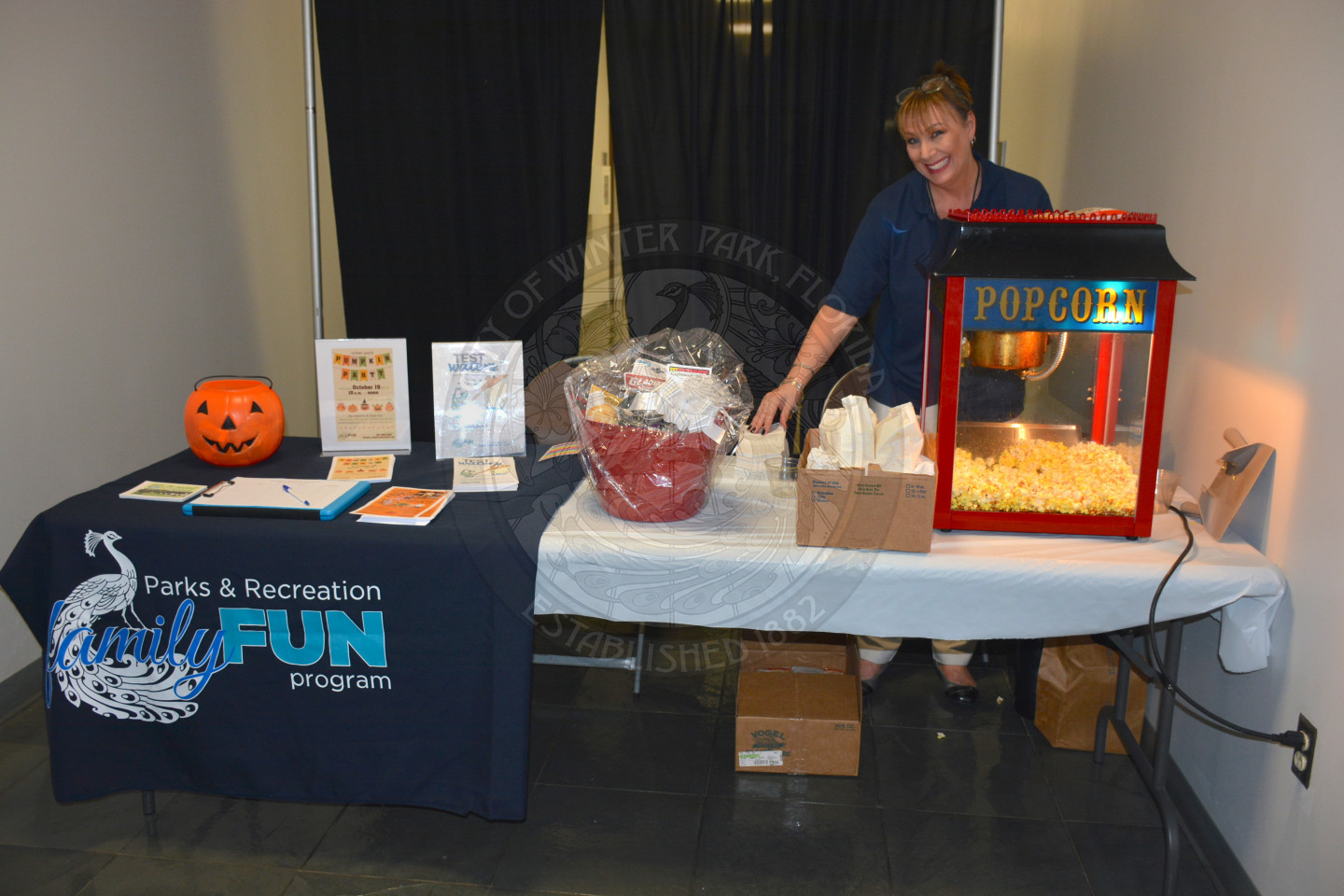 woman behind popcorn stand at display table for Parks and Recreation Family Fun Program