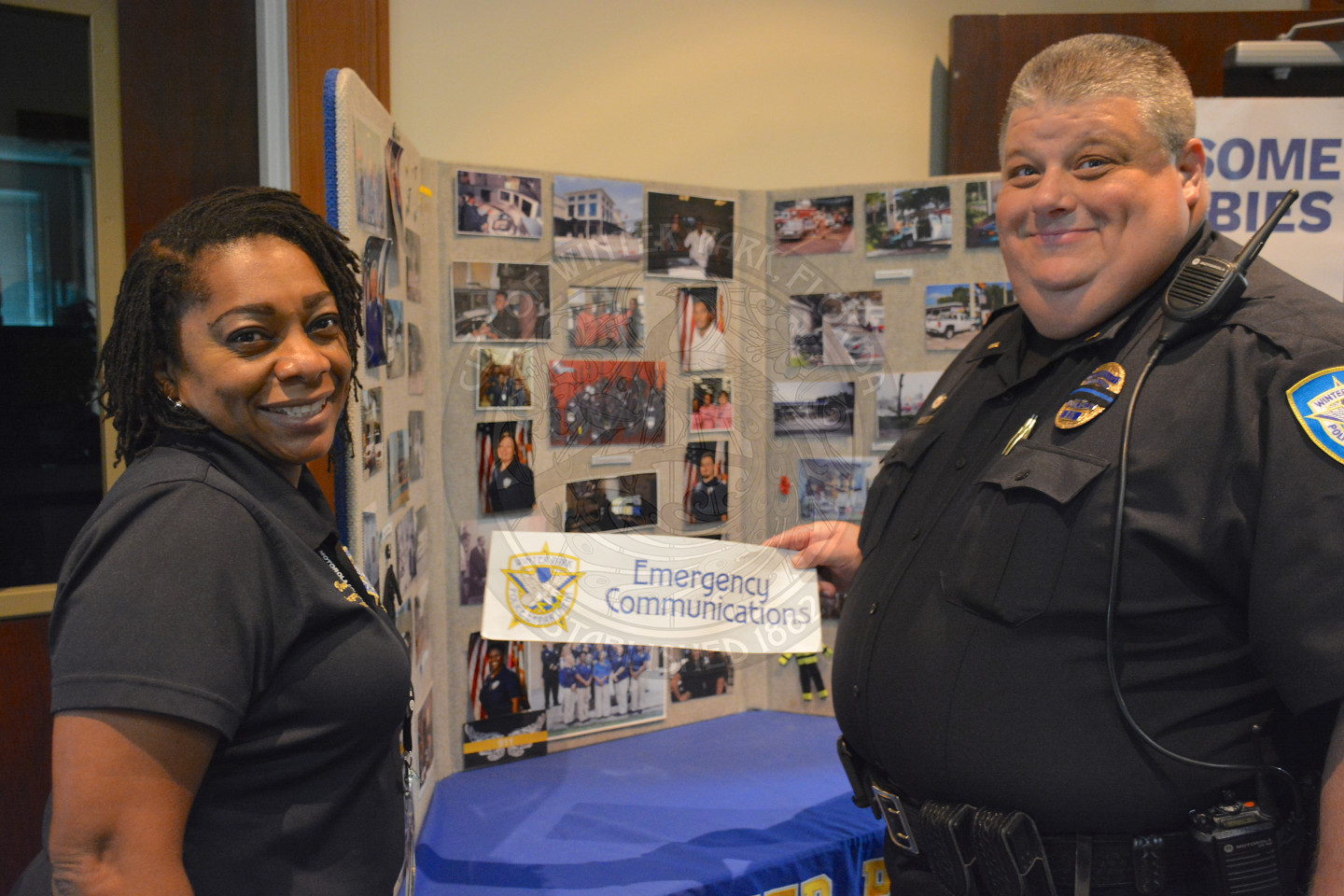 a man and woman in front of the police department Emergency Communications table
