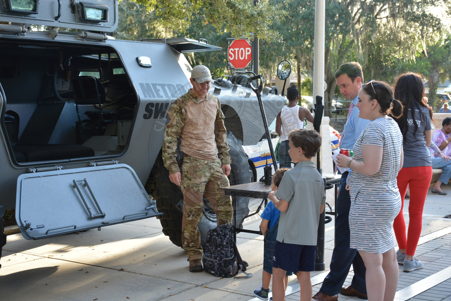 family with two small boys in front of SWAT truck with officer greeting them