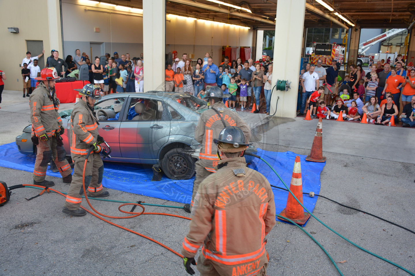 three firefighters showing audience how to extract a person from a vehicle that was in a car accident