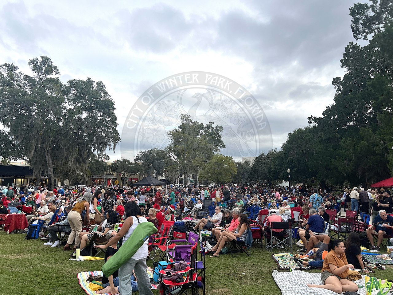 crowd full of people sitting in lawn chairs at Central park in Winter Park on Park Avenue.