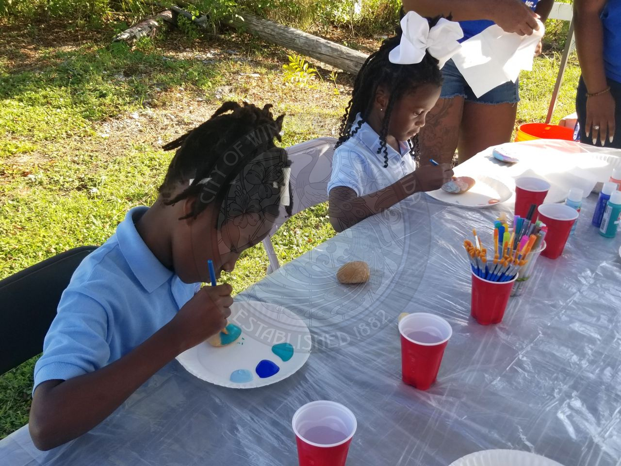2 girls sitting at a table painting rocks