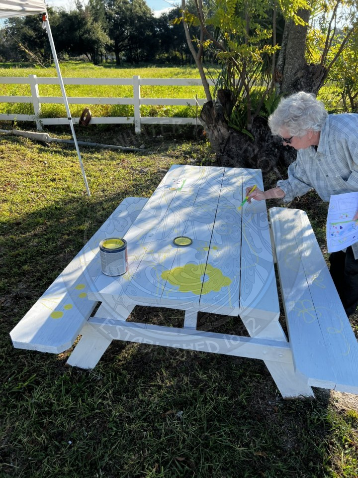 A women painting flowers on the picnic table