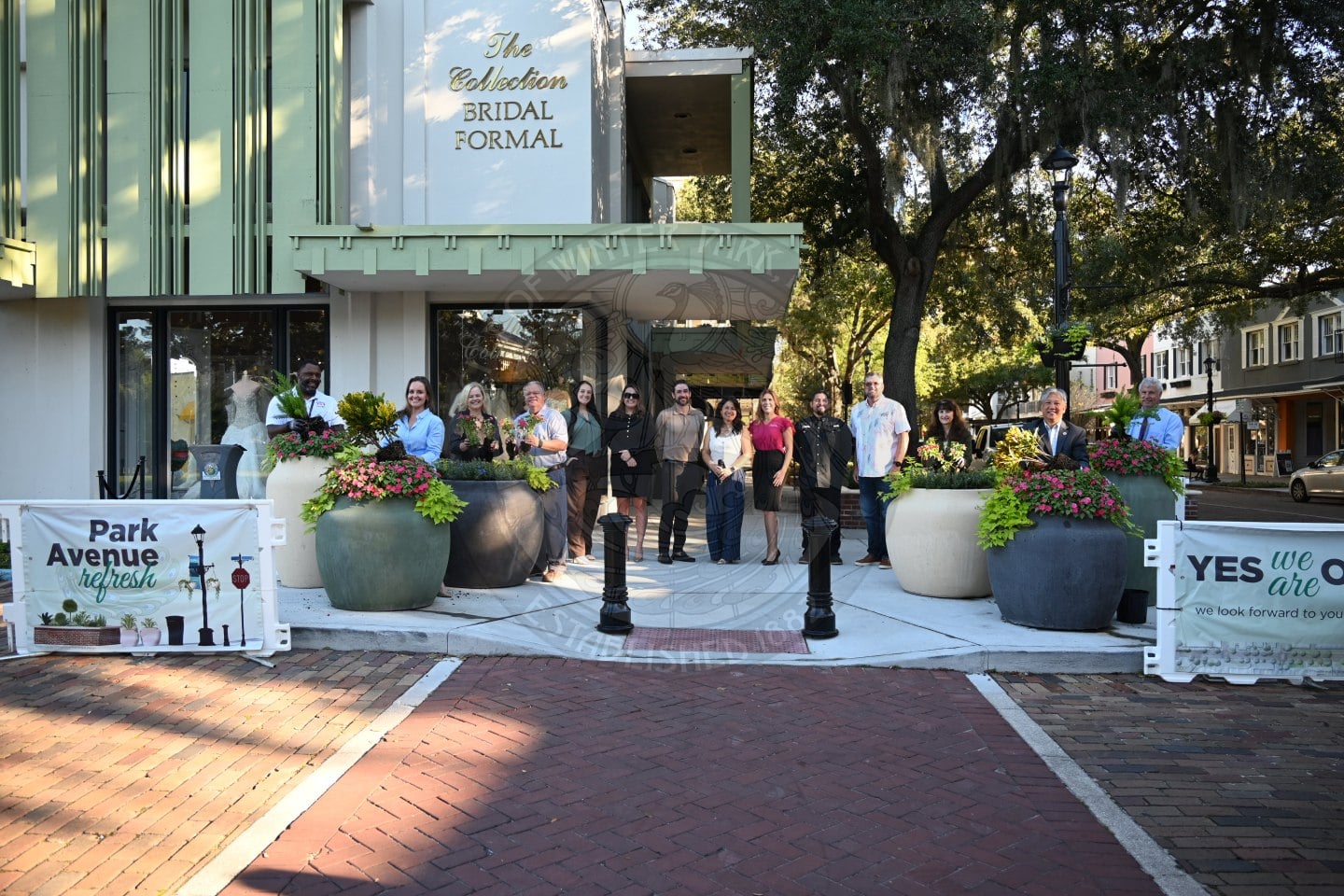 A group of people standing outside behind potted plants to celebrate phase I of Park Avenue Refresh.
