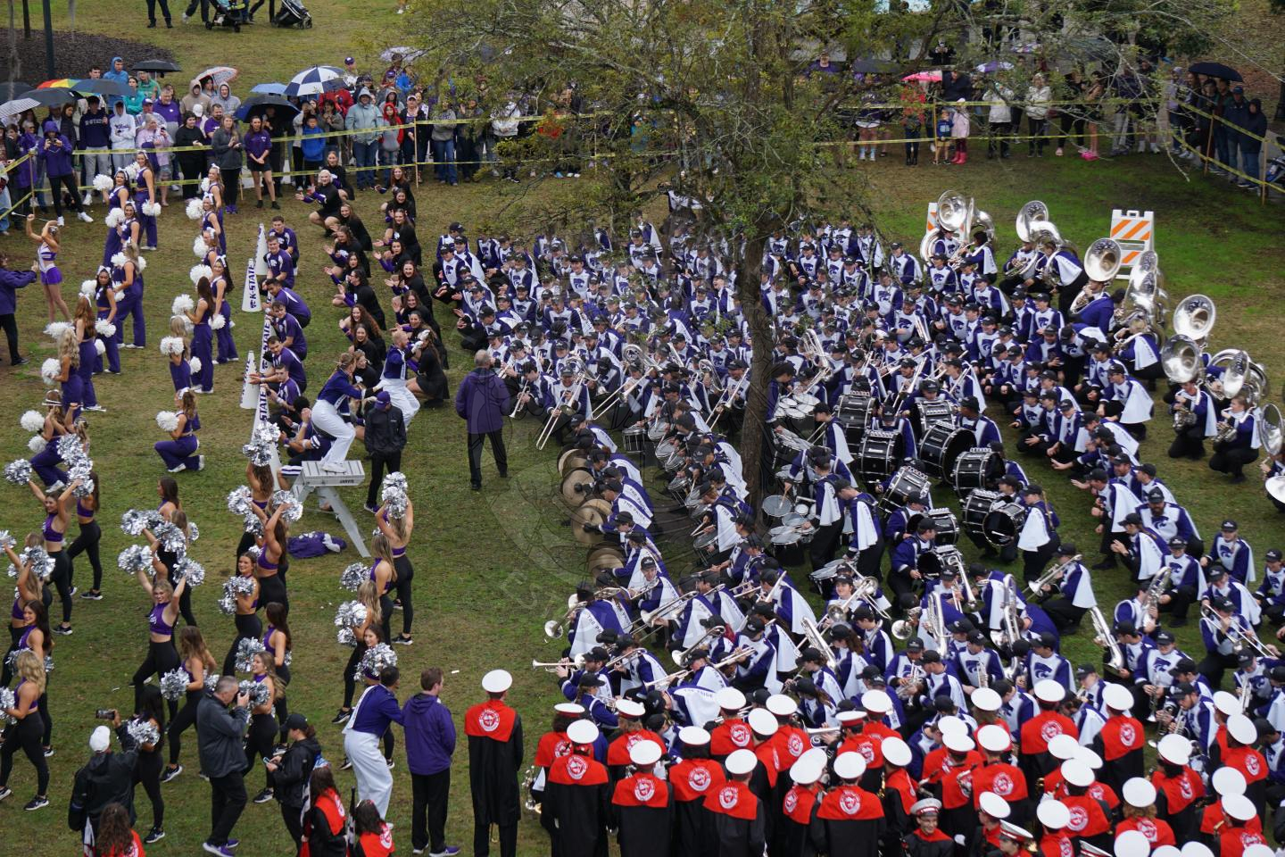 Ariel view of kansas state playing one of their classic songs where all band members start down low to the ground and play music soflty and graudally stand up as they play their instruments louder.