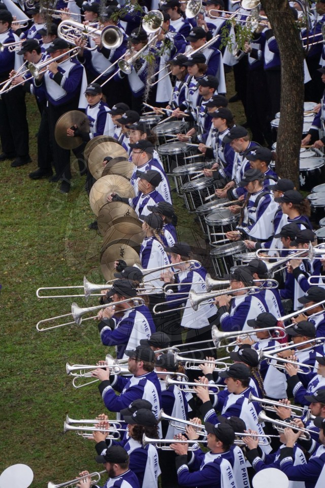 Close up from an ariel view of trombones and drum line playing their instruments.