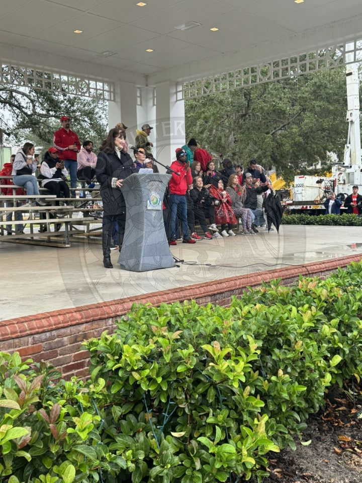 Vice Mayor Sheila DeCiccio standingbehind a podium introducing the college bands to Winter Park.