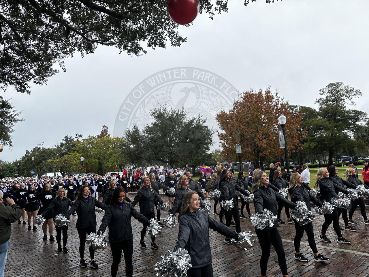 Kansas State cheerleaders clapping their pom poms while marching down Park Avenue.