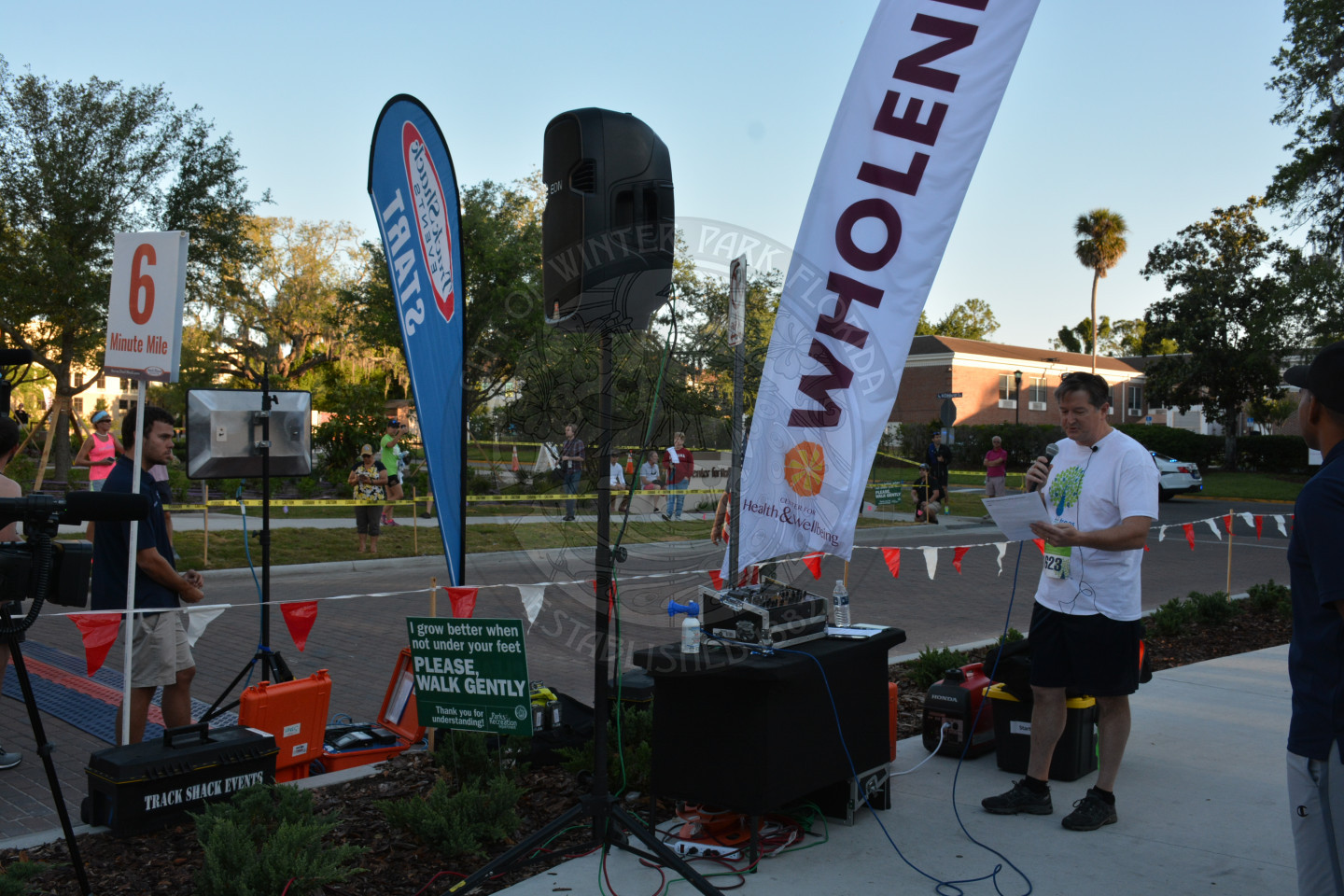 Vice Mayor Greg Seidel offers welcome remarks holding a microphone, next to race signs