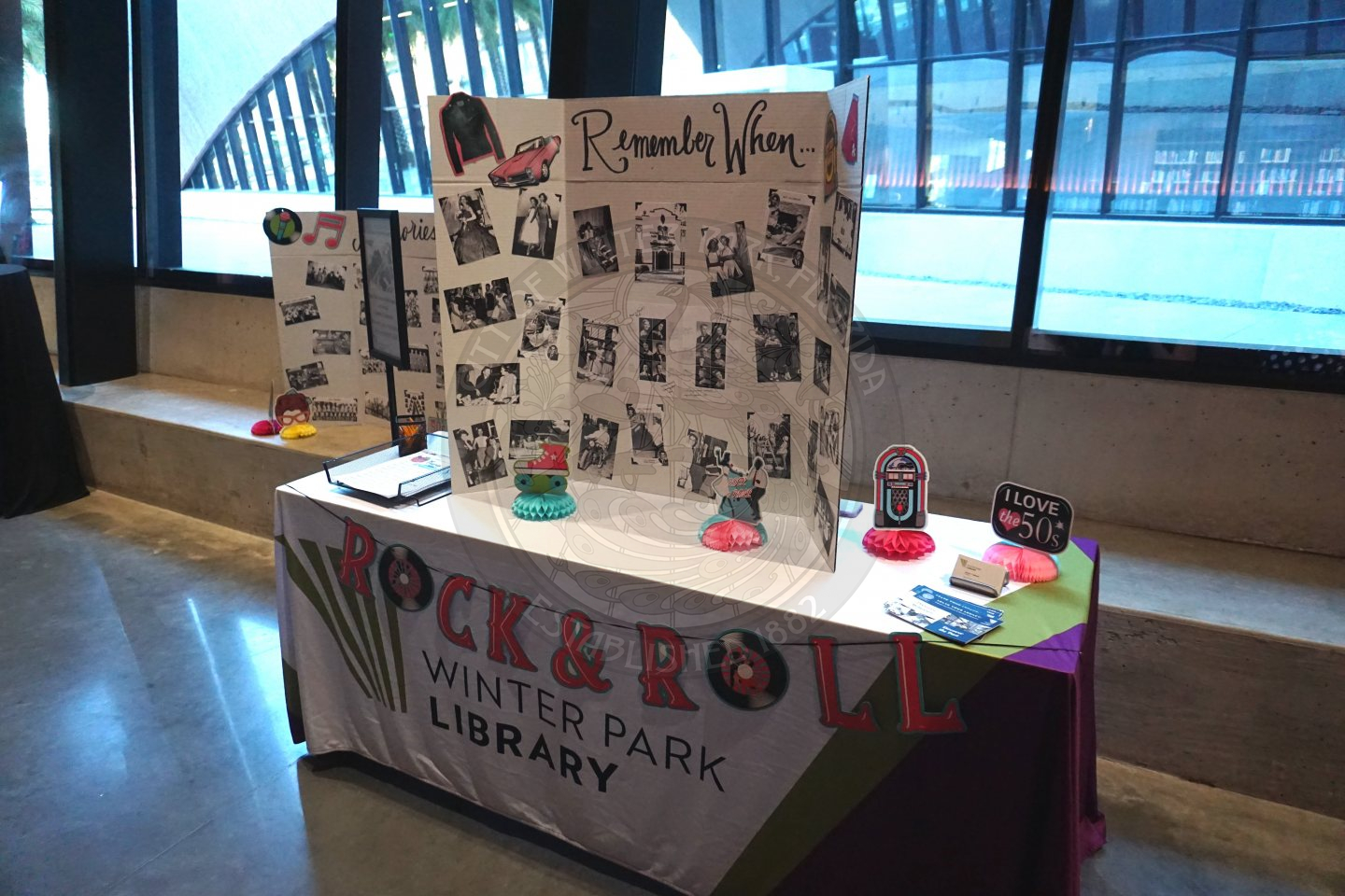 a table with a tablecloth on it that says WInter Park Library on it. There is a trifold posterboard on the table that says Remember When with black and white photos of it from the 1950s.