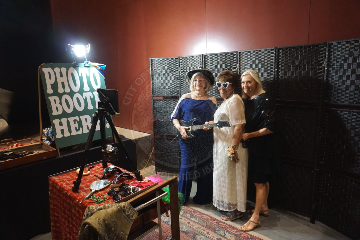 3 women standing next to each other in the photo booth area taking photos.