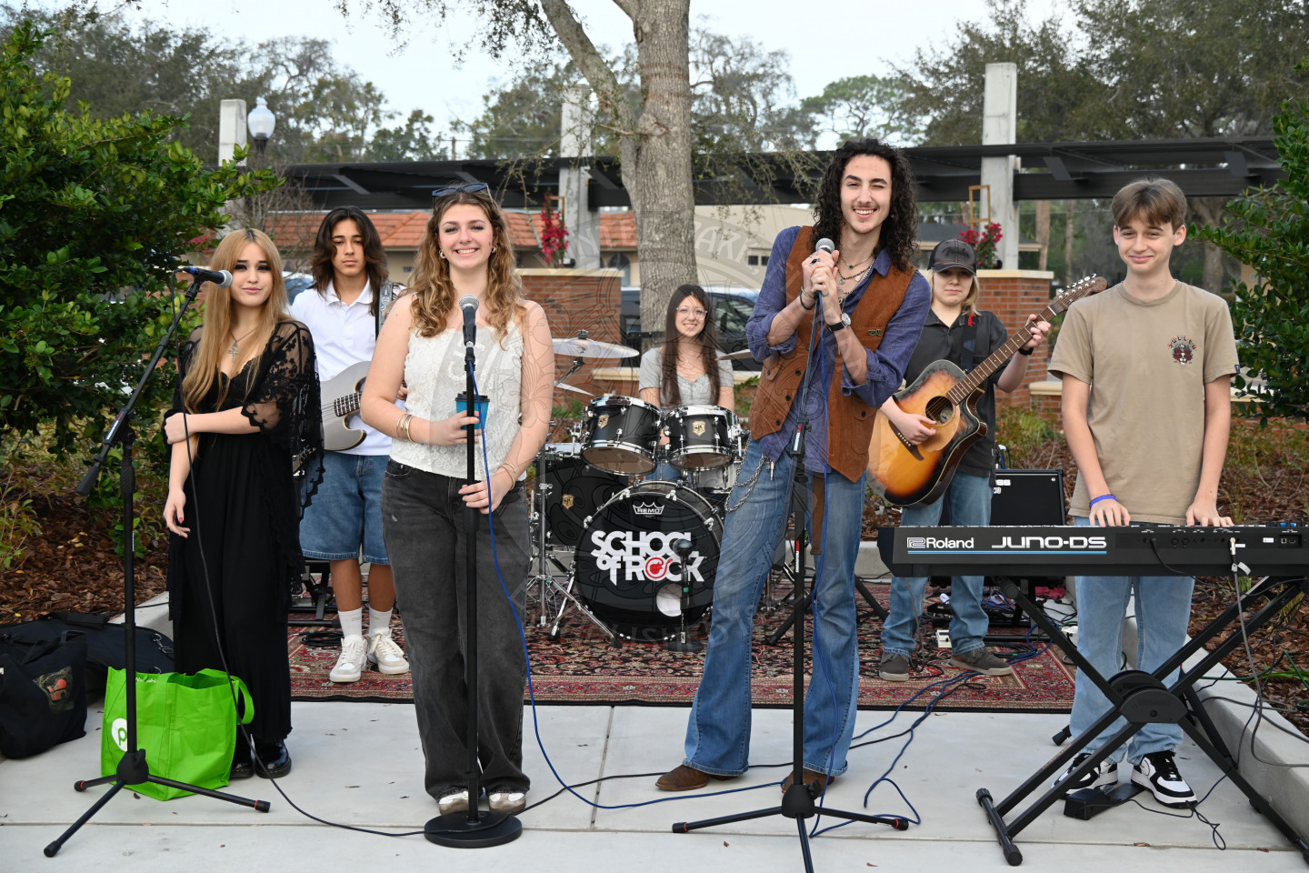 a band with three singer, a pianist, guitarist, bassist, and drums performing.