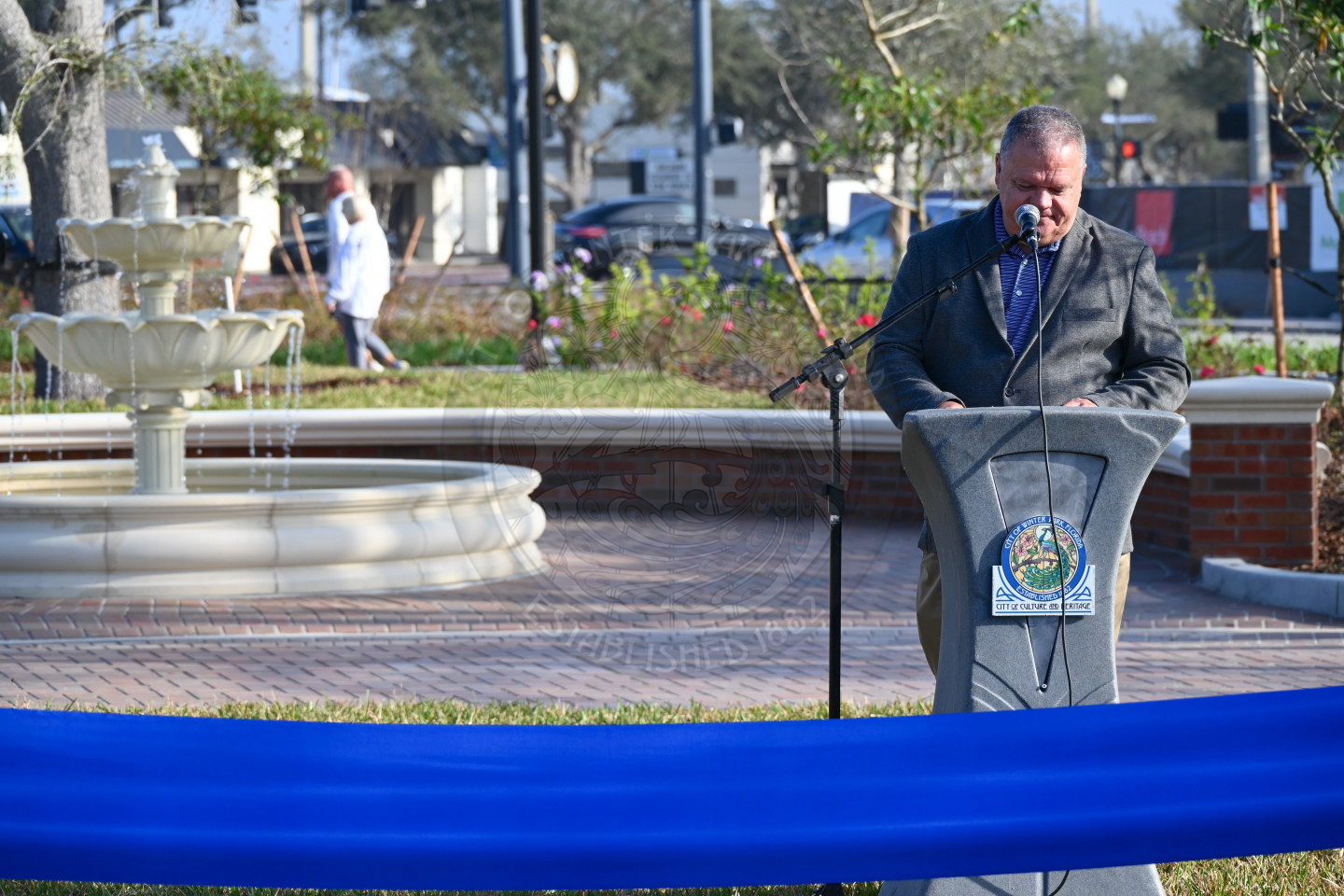 A man standing behind a podium reading off a paper while talking into the microphone.