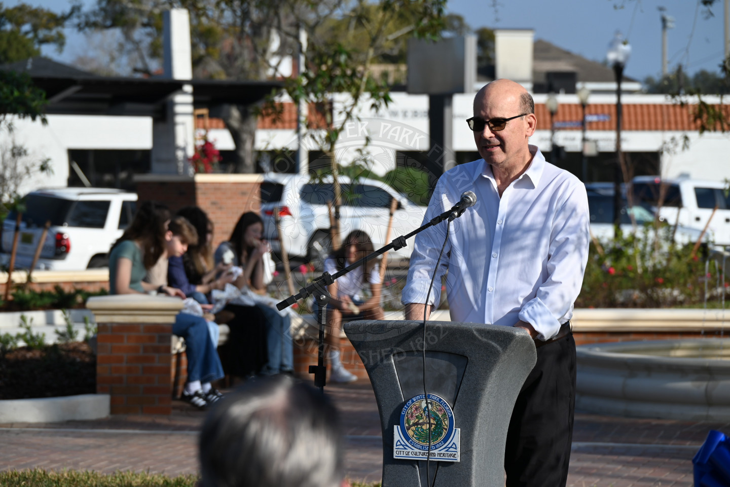 A man standing behind a podium with a microphone to his mouth talking into it.