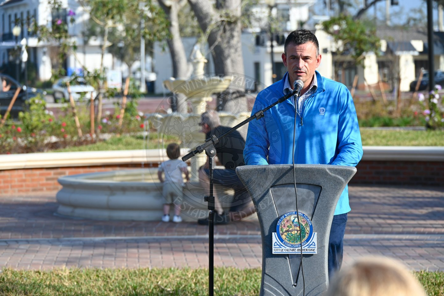 A man standing behind a podium with a microphone to his mouth talking into it.