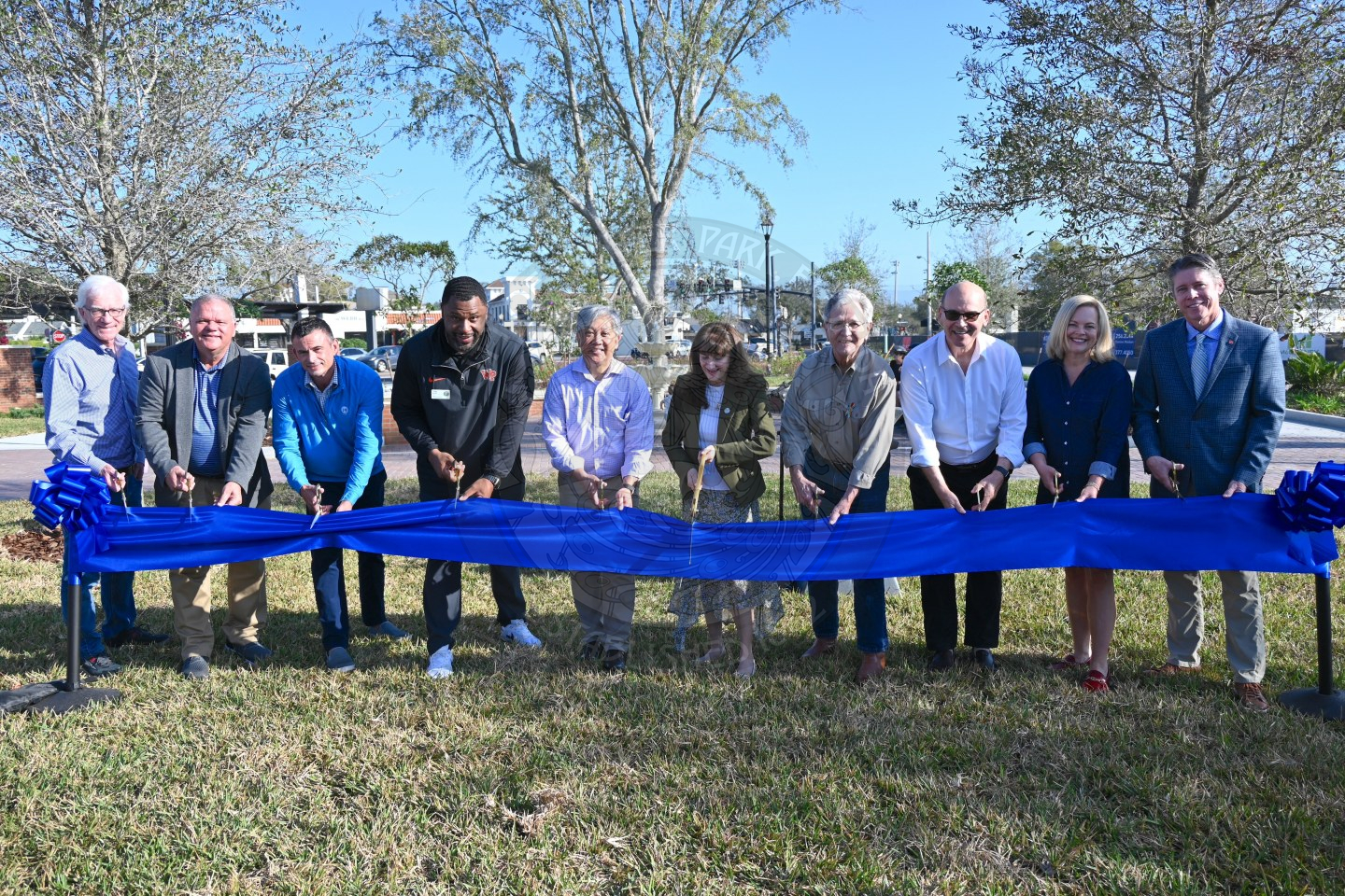 a group of people standing behind a ribbon with scissors in their hands about to cut the ribbon.