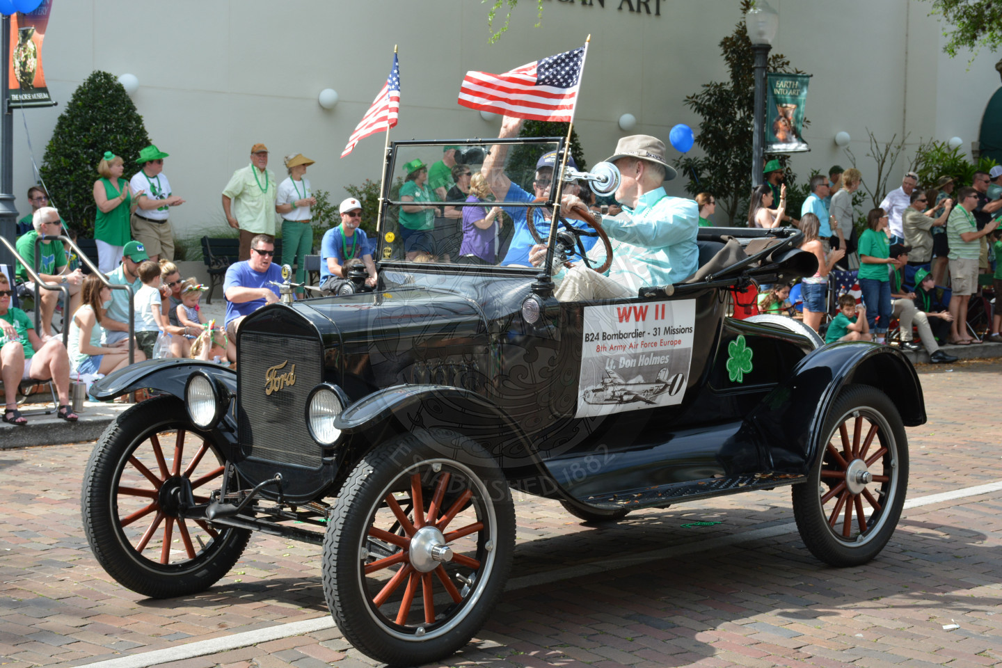 World War II Lieutenant waves from 1920s Model T car