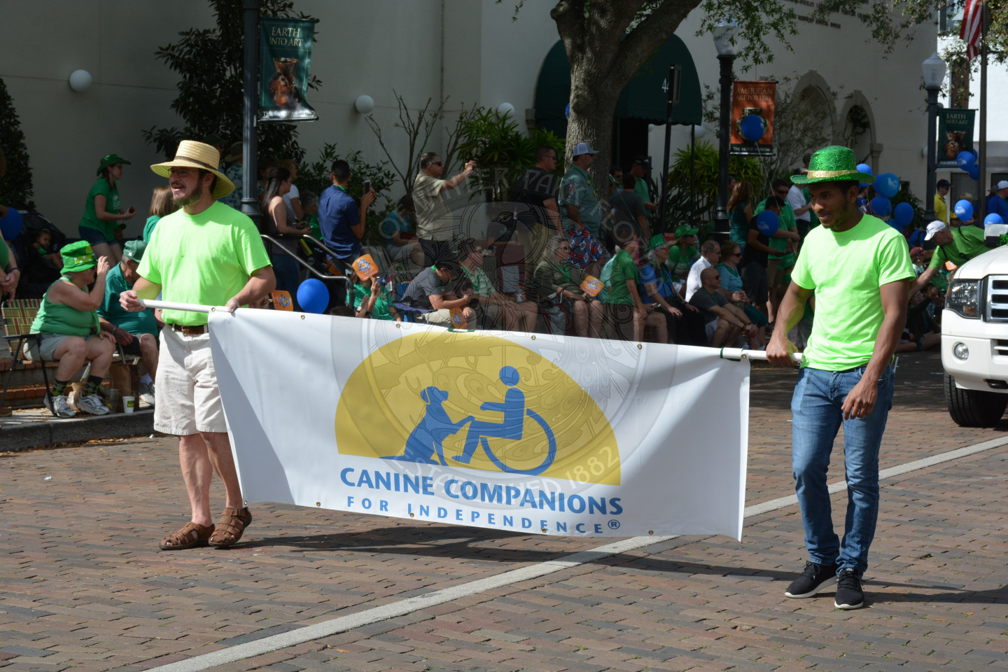 Two gentlemen holding a Canine Companions banner while walking down the parade route