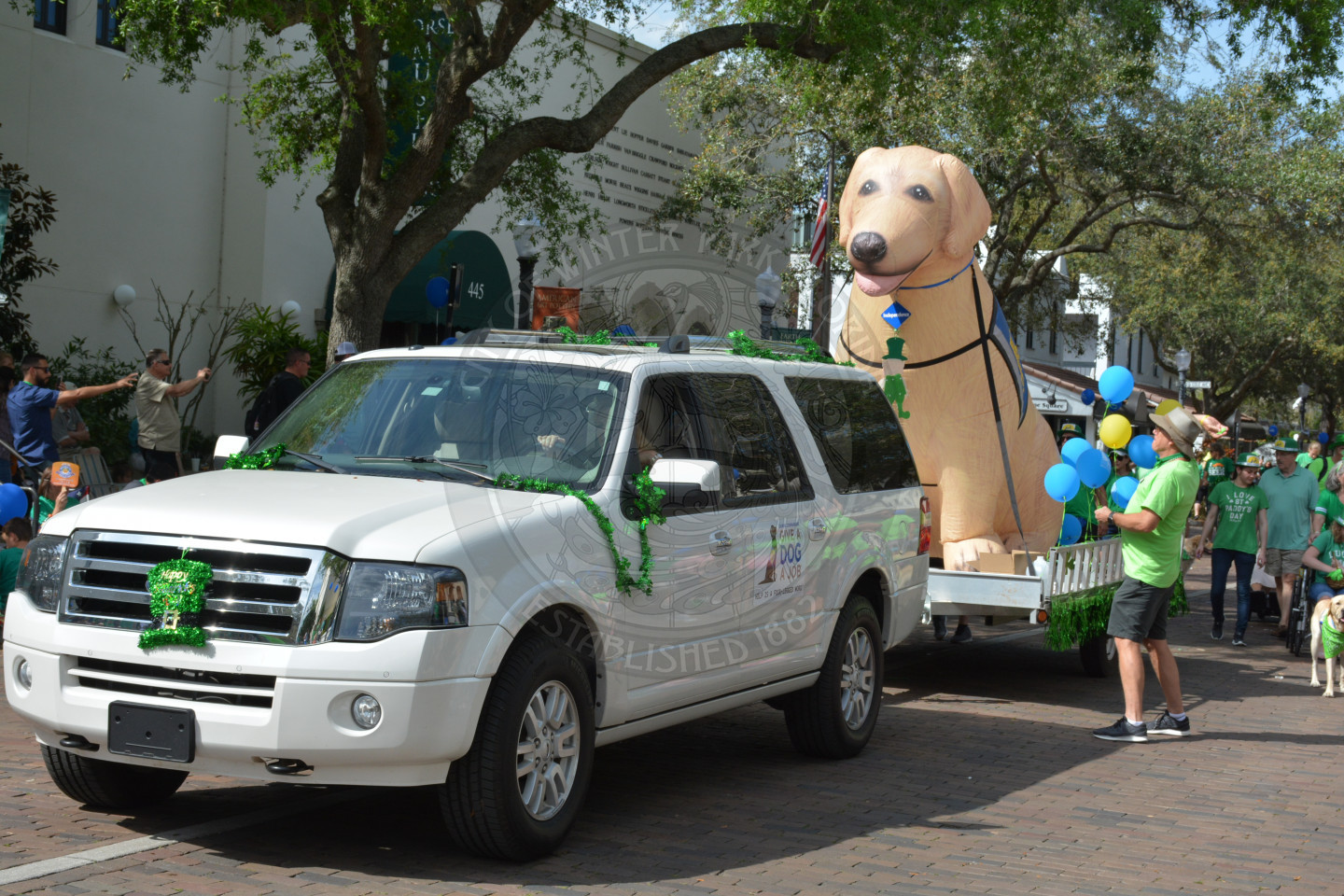 Large inflatable dog being pulled by a sports utility vehicle down the parade route