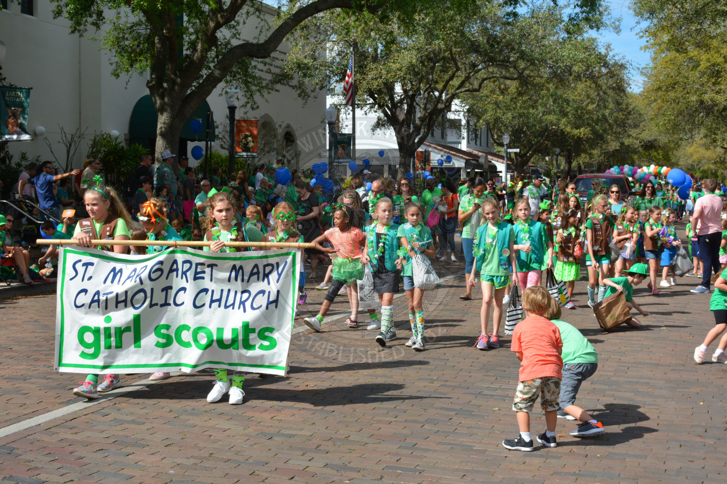 Girl scouts holding a banner as they walk down the parade route