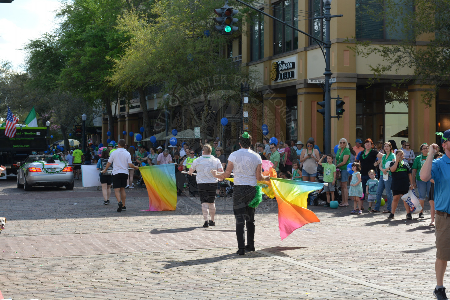 Rear view of people walking holding multi-colored flags down the parade route