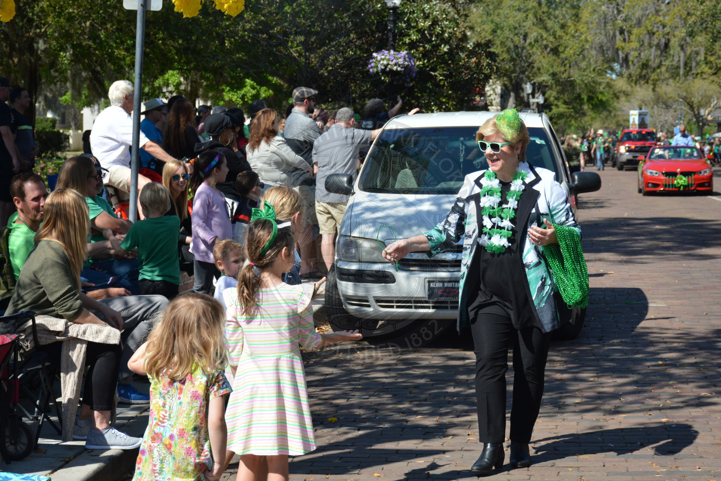 commissioner cooper passing out beads to young children in the parade