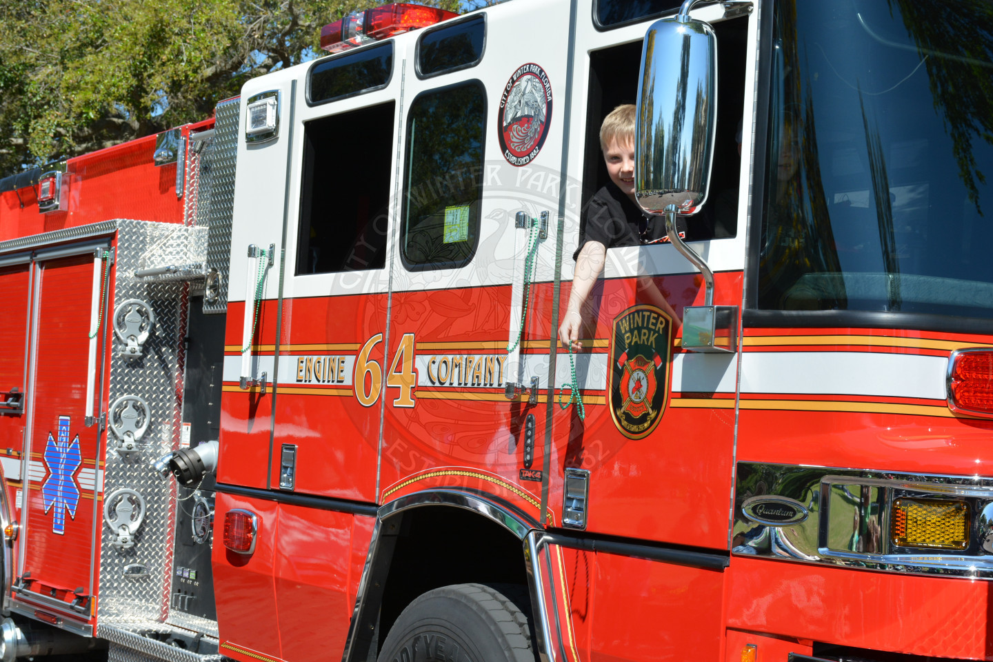 boy tossing out beads from a winter park fire-rescue engine