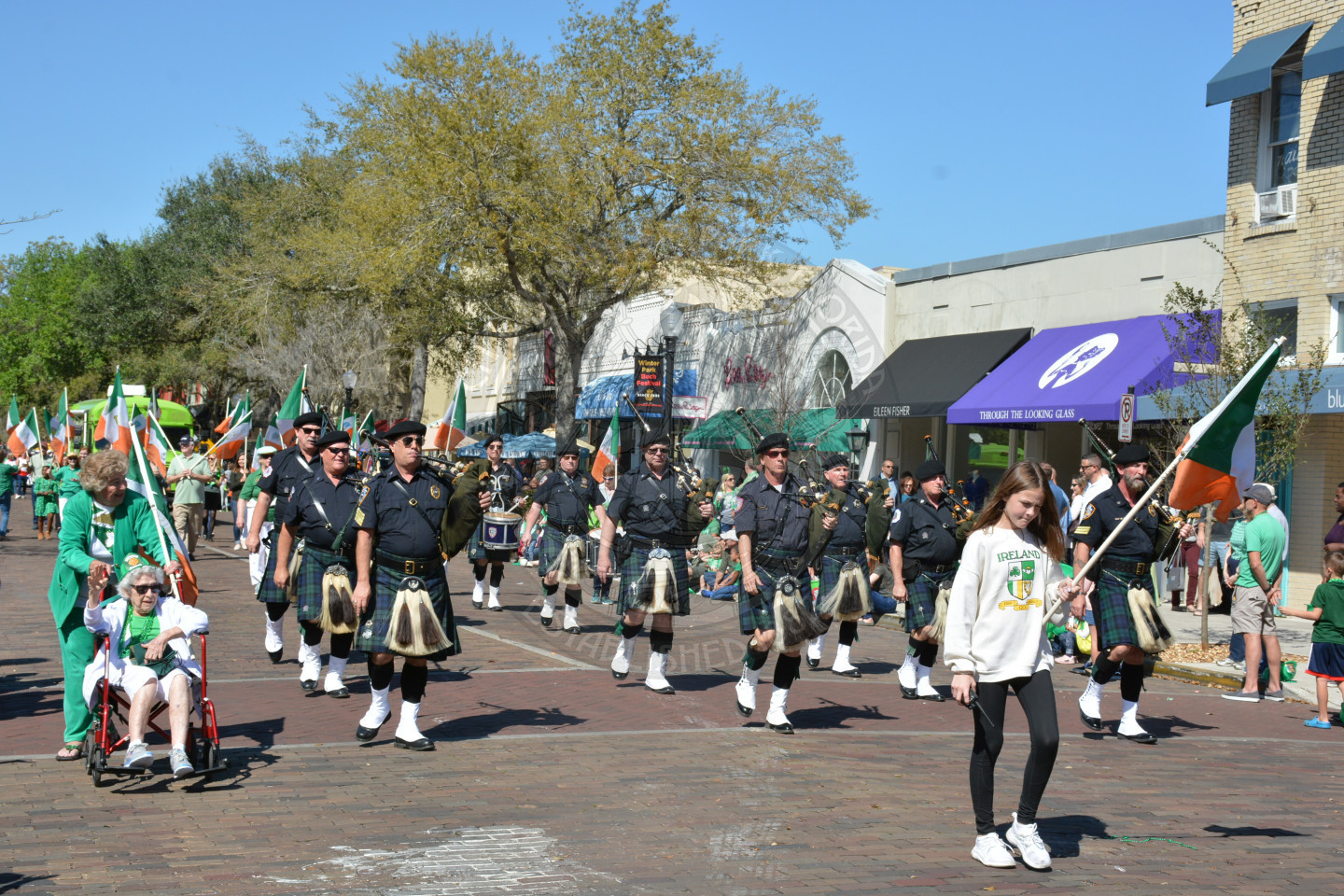 group of bagpipers walking in the parade wearing kilts