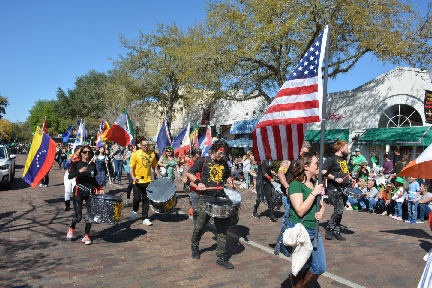 group of people holding different countries flags and playing drums in the parade