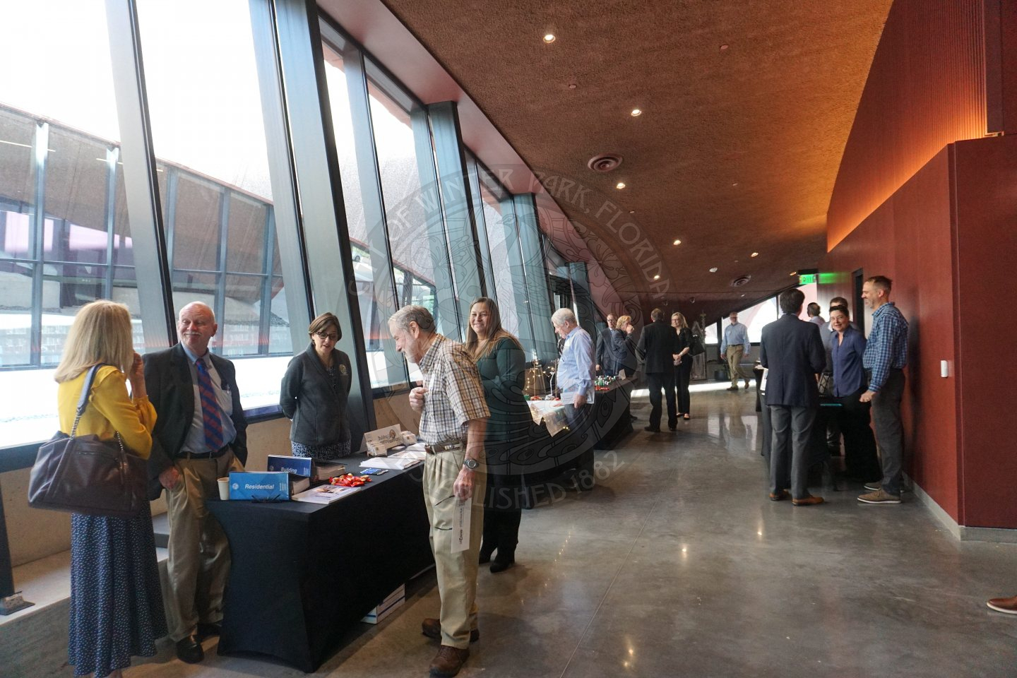 A picture of hallway with people mingling at department tables that are represented by city staff