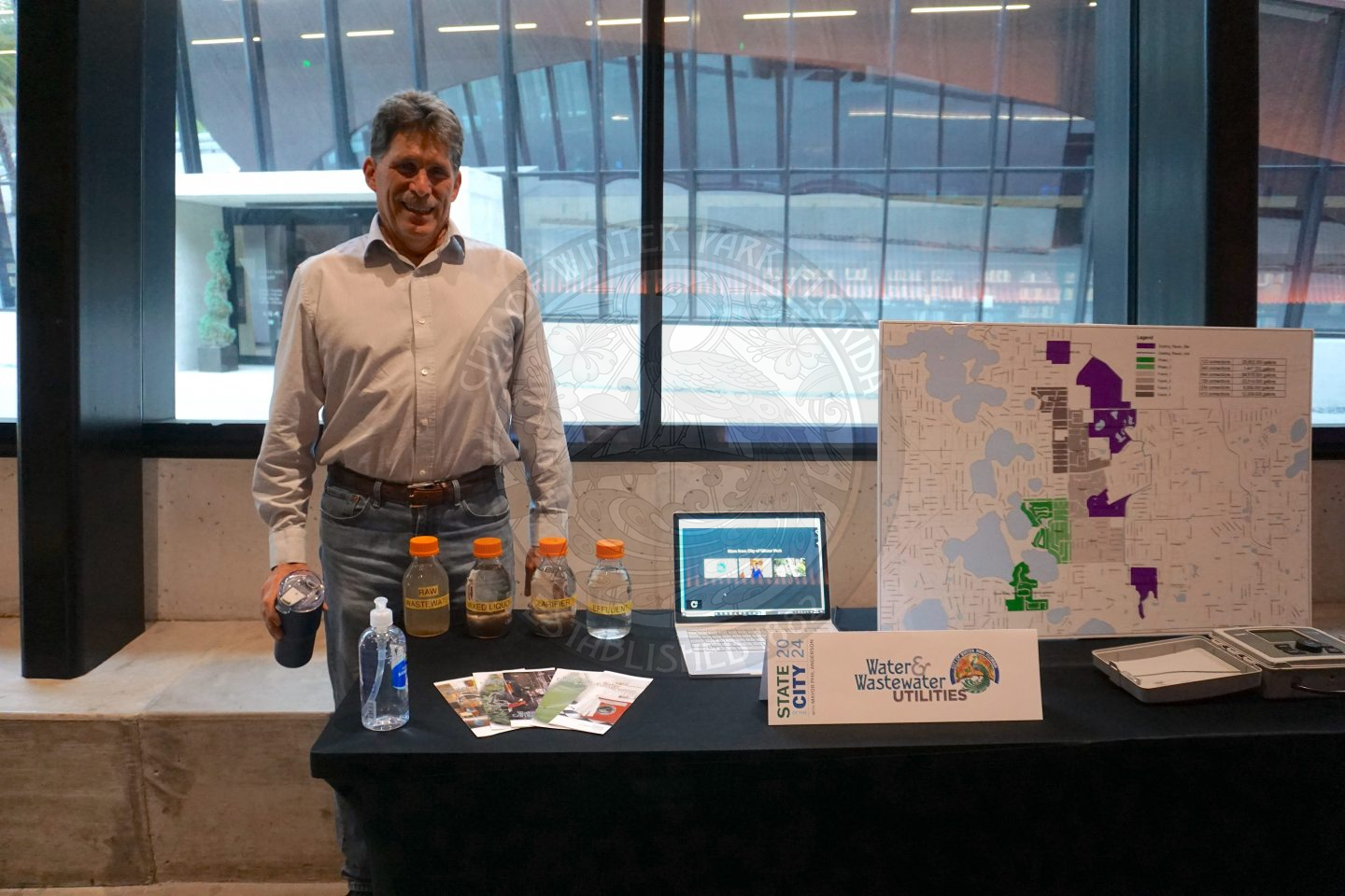 a man standing on the side/back of a table with information about the Water &amp; Wastewater Utilities Department