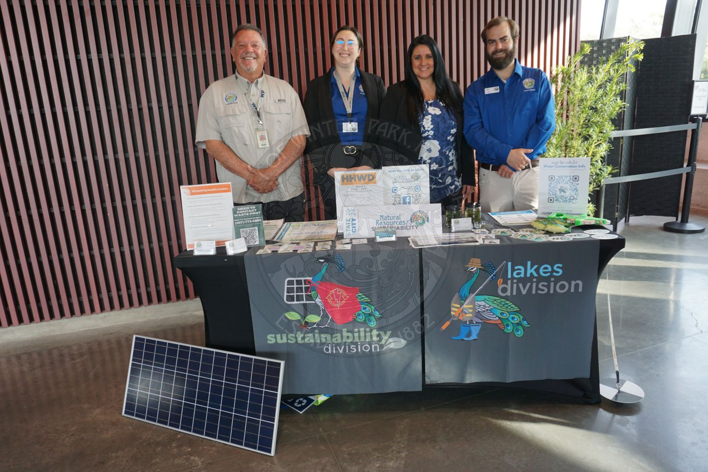 A group of employees from the city of Winter Park's Natural Resources &amp; Sustainability department standing behind the table that has a bunch of paper and promotional items explaining what their department does in the city.