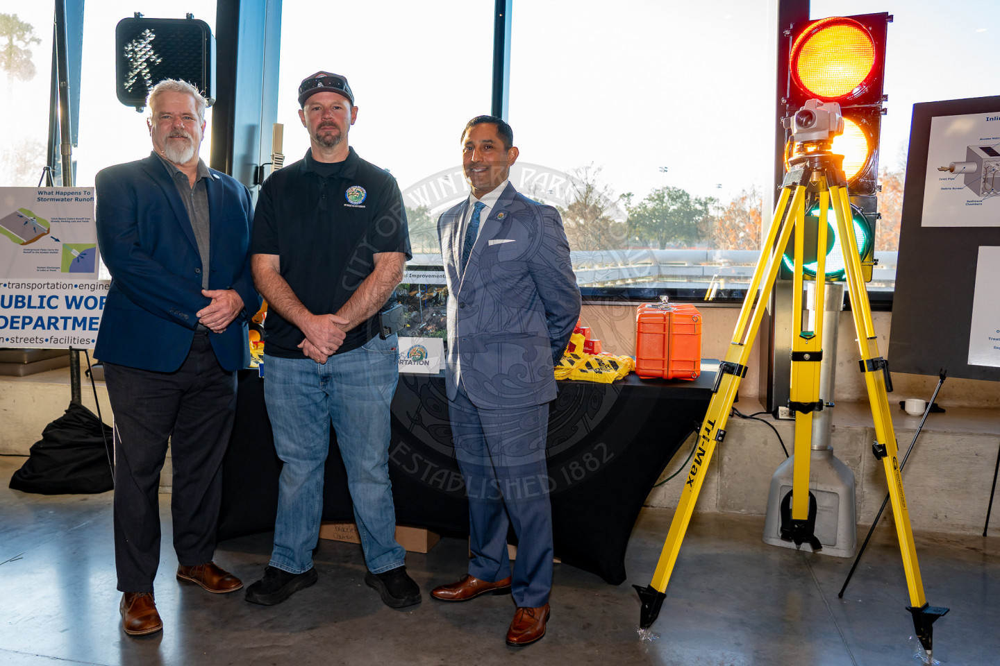 three males standing next to each other in front of a table with a traffic light next to them.