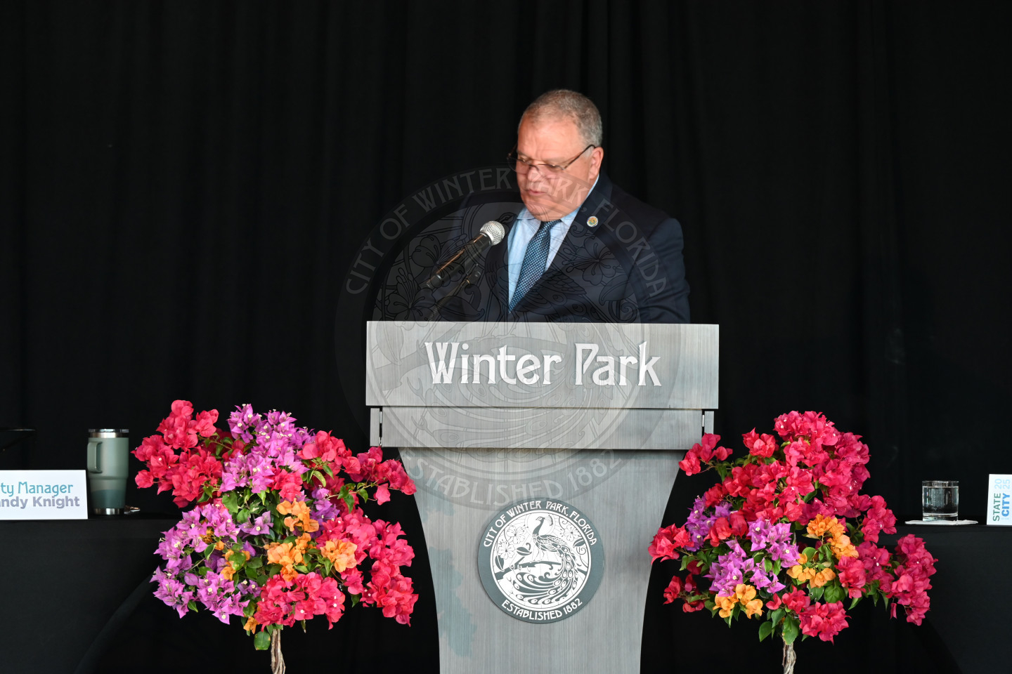 The city Manager, Randy Knight standing behind a podium that says 'Winter Park' with flowers next to the podium.