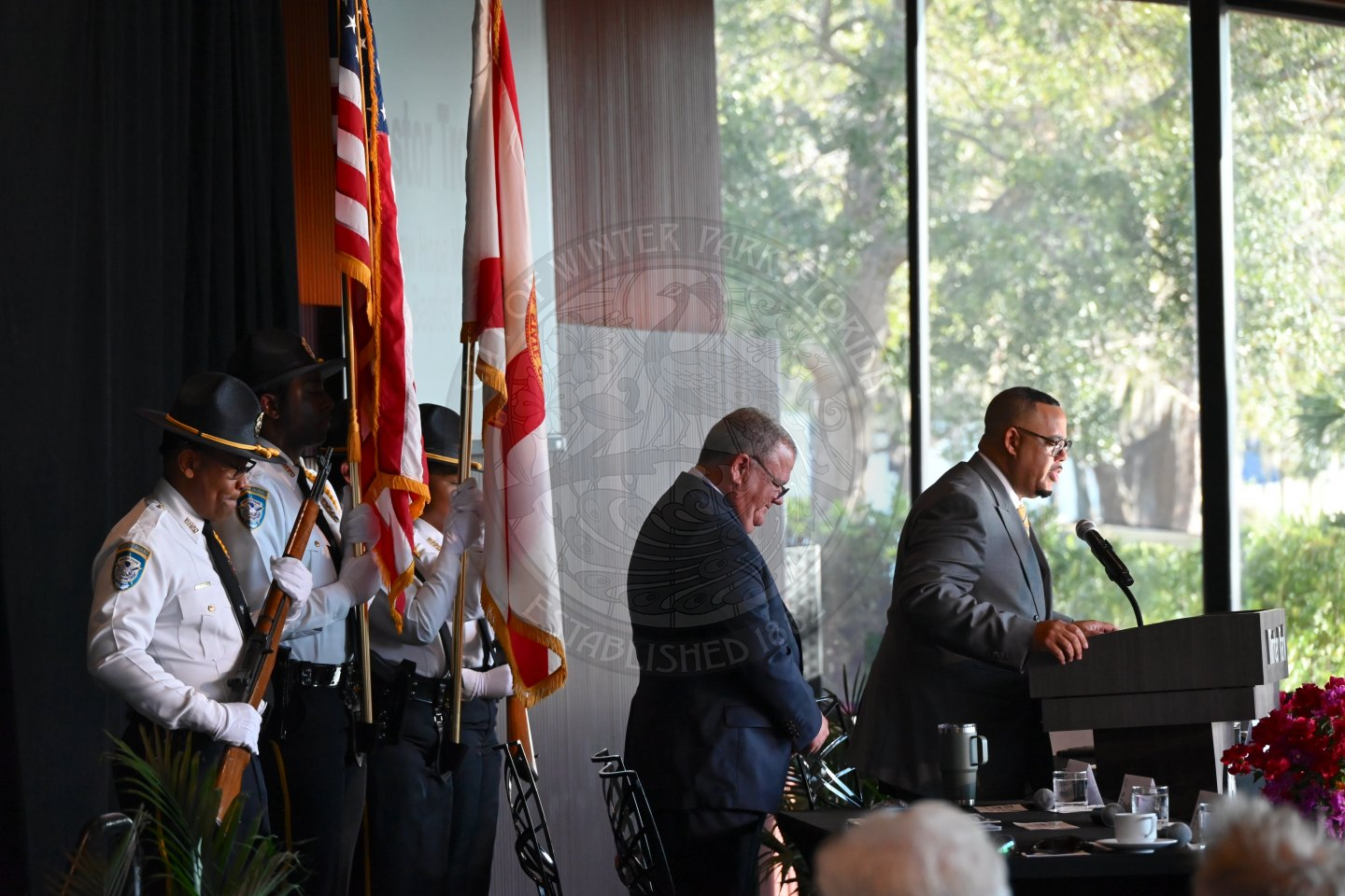 a side view of the stage with the pastor standing behind the podium saying a prayer before the program begins.
