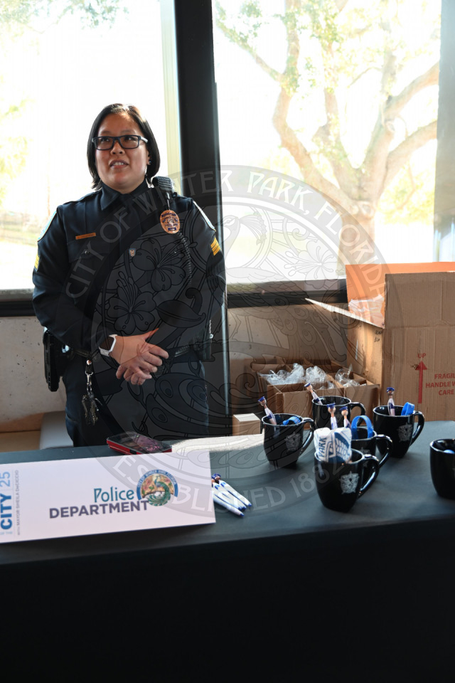 A police officer standing behind a table with police department promotional items.