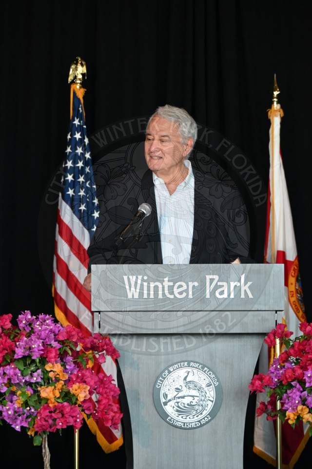 A male standing behind a podium talking to the microphone