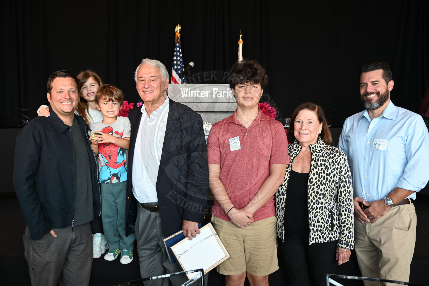 a group of family members standing in front of a stage smiling.