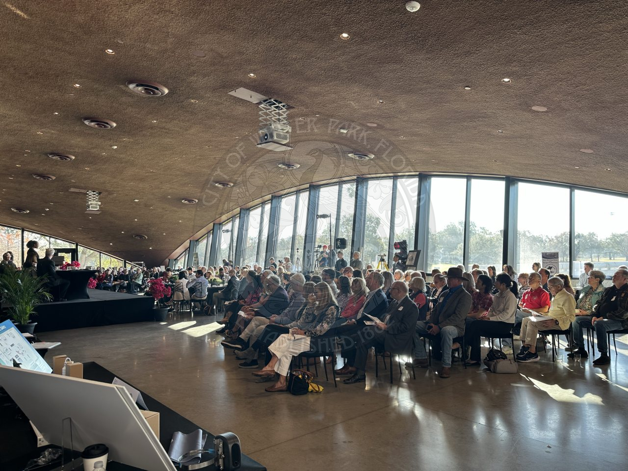 front view of attendees in seats looking at the stage while the mayor is presenting her speech.