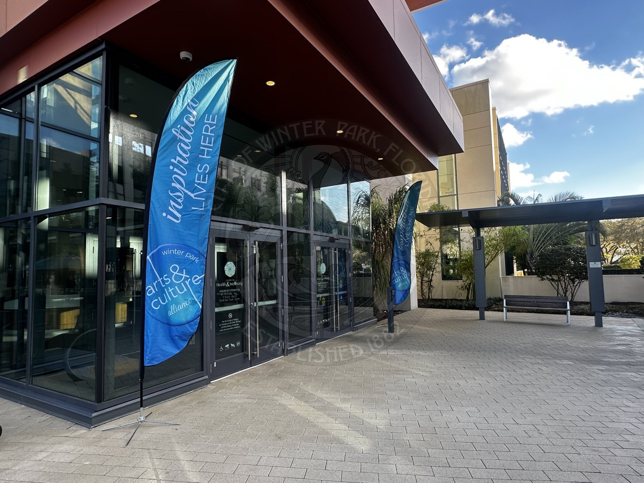 feather banners that say "inspiration lives here" in front of the doors on the outside of a building.