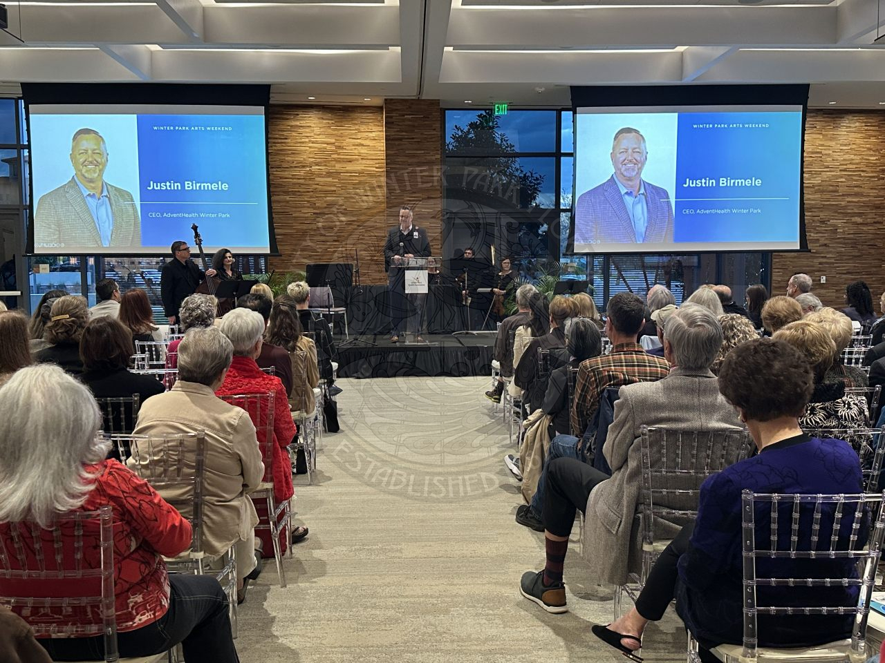 a man speaking in a room full of people talking