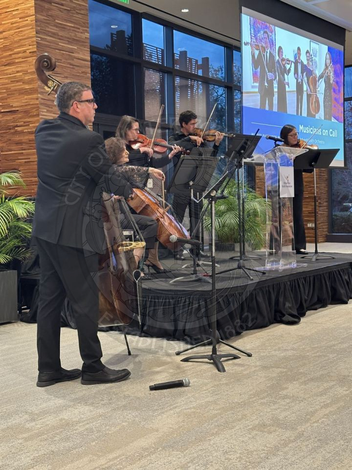 group of musicians on stage playing a cello, violin, and singing.