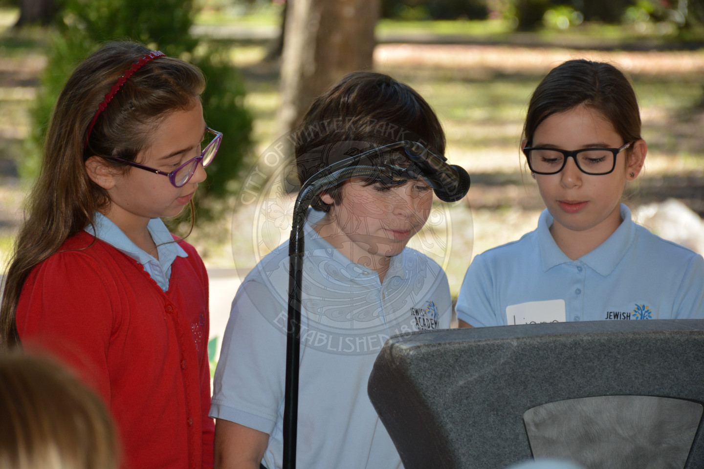 three young children sharing remarks at the podium