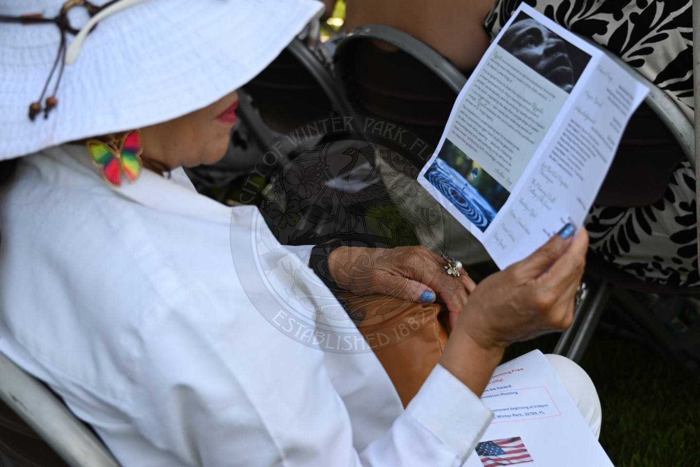 a lady reading a program that she is holding in her hand.
