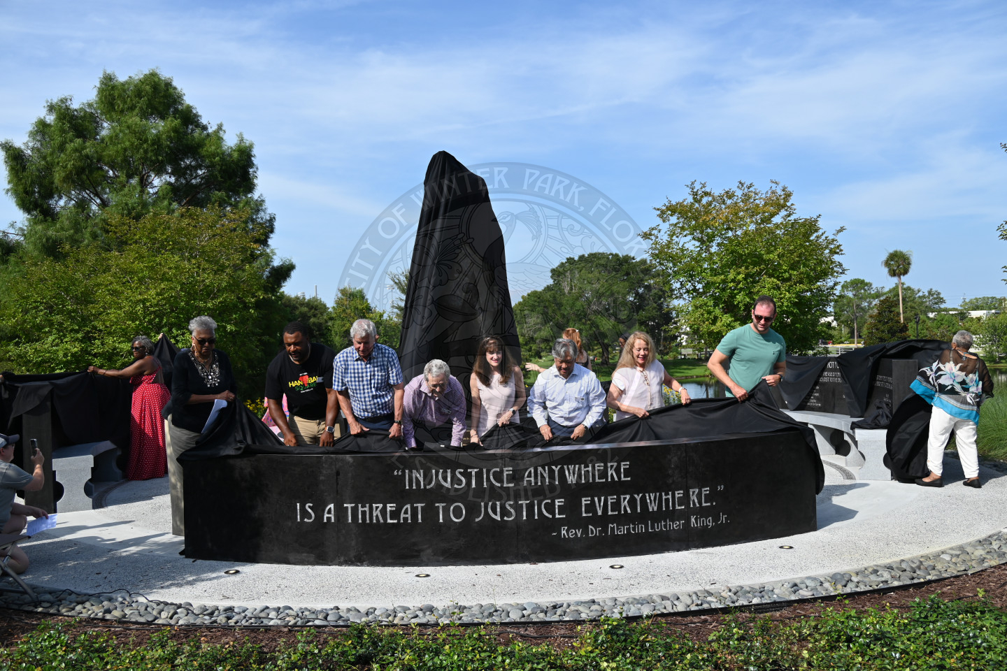 a group of people standing behind a monument unveiling what is under neath the black cloth