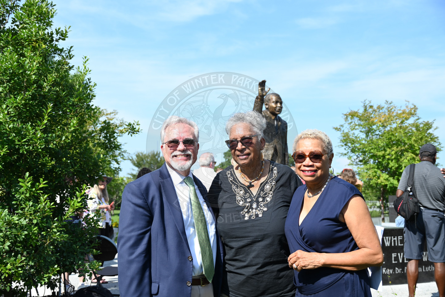 a photo of thre people smiling standing in front of a Martin Luther King, Jr. statue