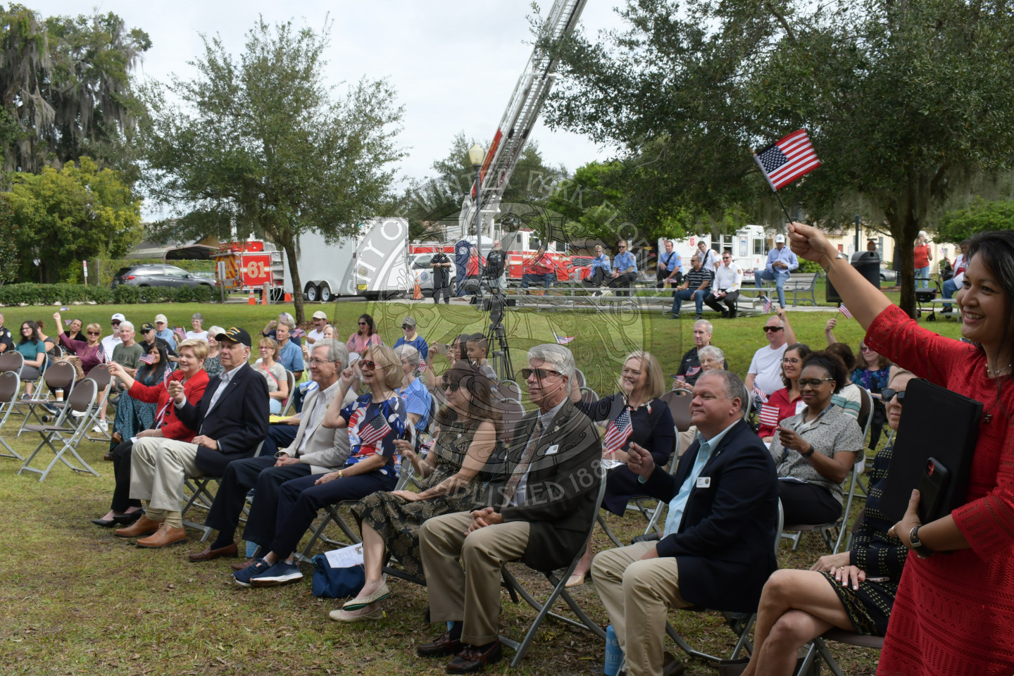 group of people sitting in chairs waving American flags