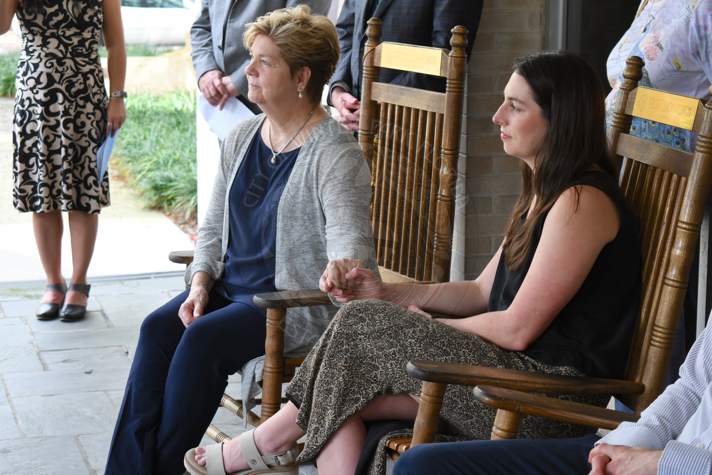 two women sitting in rocking chairs holding hands