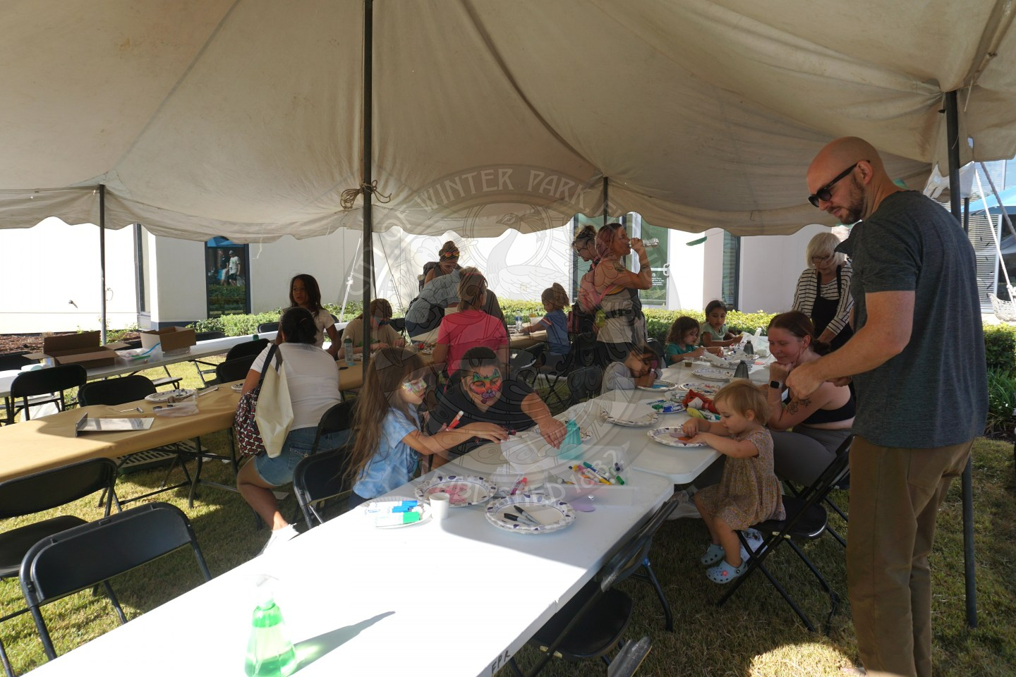 long tables under a huge white tent with arts and rafts on them for children to get creative.
